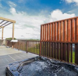 An outdoor deck with a hot tub and seating area at Adelaide in Redruth