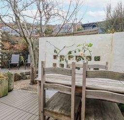 A garden with a wooden table and chairs at Cove Retreat in Penzance