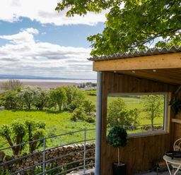An outdoor area with a table and chair overlooking greenery at Little Hut in Grange-Over-Sands