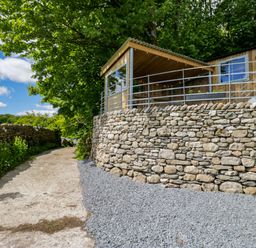 An outdoor view of a wooden structure and stone wall at Little Hut in Grange-Over-Sands