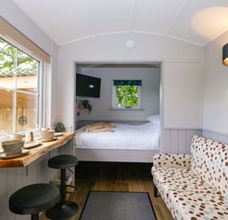A living room with a table and chairs next to a bed at Little Hut in Grange-Over-Sands