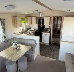 A kitchen area with a table and seating at The Beachside Hideout - St Michaels Caravan Park Towyn