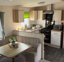 A kitchen with seating area at The Beachside Hideout - St Michaels Caravan Park in Towyn