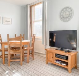 A dining room with a table and chairs with a television at Snugglers Cove in Dartmouth