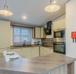 A kitchen with cabinets, sink, appliances, and dining items at Brayford Lodge (Pet) Louth