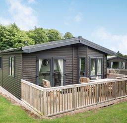 A lodge with a wooden deck and chairs at Brayford Lodge (Pet) in Louth