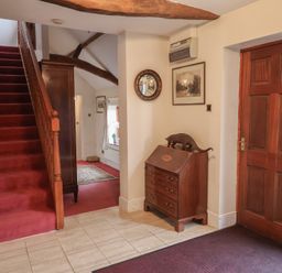 A hallway with a staircase and wooden chest of drawers at Winston Lodge in Beccles