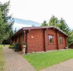 A log cabin with a pathway and garden area at Little Bears Hideaway @ 23 Lakeside Felmoor Park near Felton
