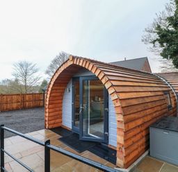 A wooden cabin with a curved roof and door at Park View Lodge