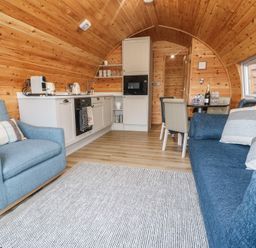 A living room with a sofa and kitchen area at Park View Lodge
