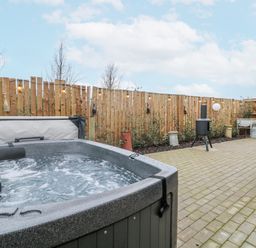 An outdoor area with a hot tub and a fence at The Sty in Hatton, Derbyshire