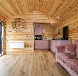 A living room with a sofa and kitchen unit at The Sty in Hatton, Derbyshire