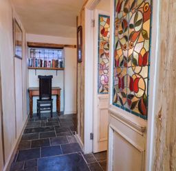A hallway with stained glass windows and a desk at Rope Cottage in Bridport