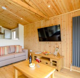 A living room with a sofa, television, and coffee table at The Sutton in Kings Cliffe