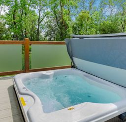 A hot tub on a deck surrounded by trees at The Wansford in Kings Cliffe