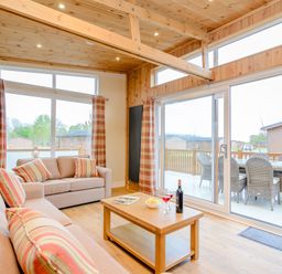 A living room with a sofa, coffee table, and large windows at The Wansford in Kings Cliffe