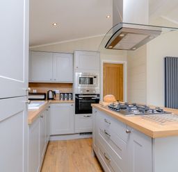 A kitchen with cabinets and an island showing an oven and stove at The Ailsworth (Pet) Kings Cliffe