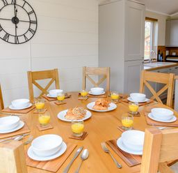 A dining room with a round table set for breakfast at The Ailsworth (Pet) Kings Cliffe