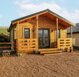 A log cabin with steps and gravel area at Glenview Log Cabin in Ballycastle