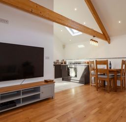 A dining area with a television and kitchen at The Maisonette in Hayle