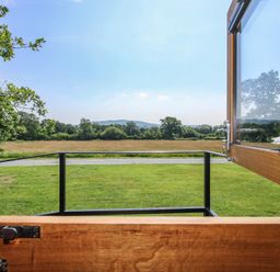 A view of grass and trees from a window at Dave’s Place in Broadstone near Munslow