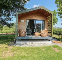 A cabin with a deck and seating area at Leafy Oaks Cabin in Munslow