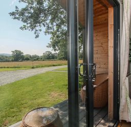 A view from a cabin door with a chair and table at Leafy Oaks Cabin in Munslow