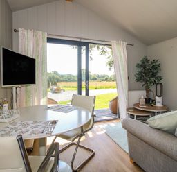 A living room with a dining table and television at Leafy Oaks Cabin in Munslow