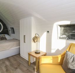 A bedroom with a bed, nightstand, and armchair at Garden Lodge 5 in Swansea