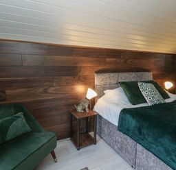 A bedroom with a bed and a chair at Garden Lodge 7 Swansea