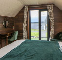 A bedroom with a bed and a mirror at Garden Lodge 8 in Swansea
