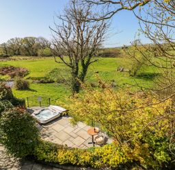 An outdoor area with a hot tub and a table with chairs at Rose Apartment Old Walls, Llanrhidian, Gower