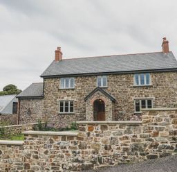 A house with a stone facade and a brick wall at Knowle House Okehampton
