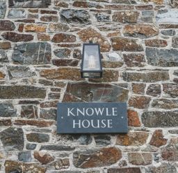 A wall with a nameplate and light fixture at Knowle House Okehampton