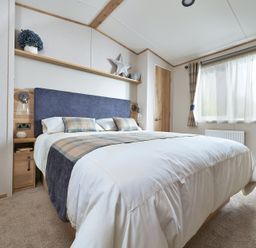 A bedroom with a bed and bedside table at Juniper Waterside Spa Carlton Miniott near Thirsk