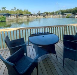 An outdoor terrace with a table and chairs at Acacia Waterside Spa, Carlton Miniott near Thirsk