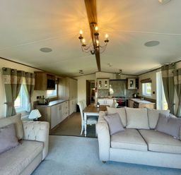 A living room with a sofa, dining table, and kitchen at Acacia Waterside Spa Carlton Miniott near Thirsk