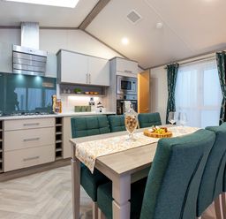 A kitchen with modern appliances and a dining table at Rowan Waterside Spa Carlton Miniott near Thirsk
