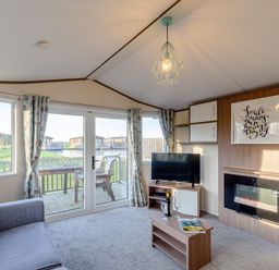 A living room with a television and a fireplace at Alder Spa in Carlton Miniott near Thirsk