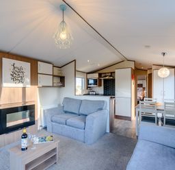A living room with a sofa and dining table at Alder Waterside Spa Carlton Miniott near Thirsk