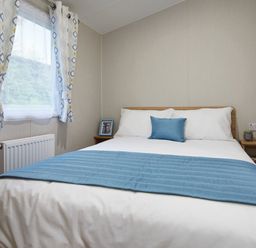 A bedroom with a bed and side table at Banyan Waterside Spa Carlton Miniott near Thirsk