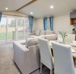 A living room with a dining area and exit to outdoor space at Banyan Waterside Spa in Carlton Miniott near Thirsk