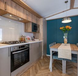 A kitchen with a gas stove and dining table at Ellery Waterside Spa in Carlton Miniott near Thirsk