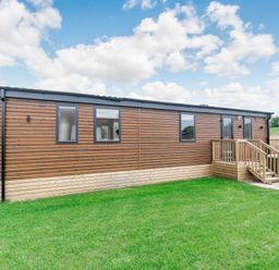 A wooden cabin with steps and windows in an outdoor area at Cedar Spa (Pet) Carlton Miniott near Thirsk
