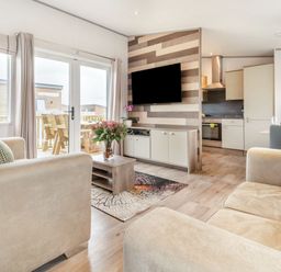 A living room with a sofa, coffee table, and television at Kinder Spa in Carlton Miniott near Thirsk