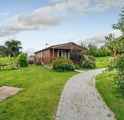 A cabin with a pathway and seating area at Fir Tree Waterside Spa Carlton Miniott near Thirsk
