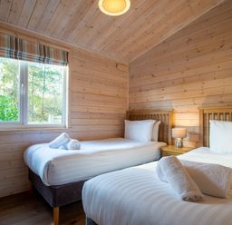 A bedroom with two single beds and a window at Fir Tree Waterside Spa in Carlton Miniott near Thirsk