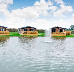 Three cabins by a lake with a fountain at Spindle Spa Carlton Miniott near Thirsk
