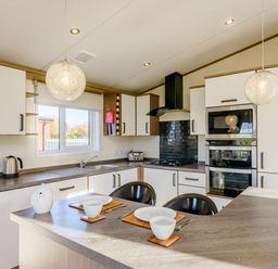 A kitchen with modern appliances and dining setup at Oak Waterside Spa (Pet) Carlton Miniott near Thirsk