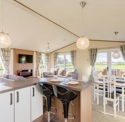 A living room with a sofa, television, and dining area at Oak Waterside Spa (Pet) Carlton Miniott near Thirsk
